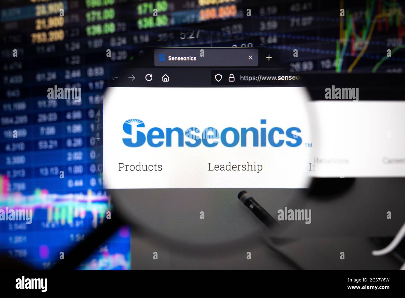 Logo aziendale Senseonics su un sito Web con sviluppi sfocati del mercato azionario sullo sfondo, visto su uno schermo del computer attraverso una lente di ingrandimento Foto Stock