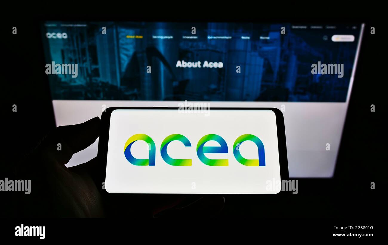 Titolare di un telefono cellulare con logo della società di servizi italiana ACEA S.p.A. sullo schermo davanti alla pagina web aziendale. Mettere a fuoco il display del telefono. Foto Stock