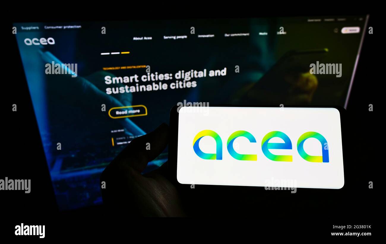 Persona titolare del cellulare con logo della società di servizi italiana ACEA S.p.A. sullo schermo davanti alla pagina web aziendale. Mettere a fuoco il display del telefono. Foto Stock