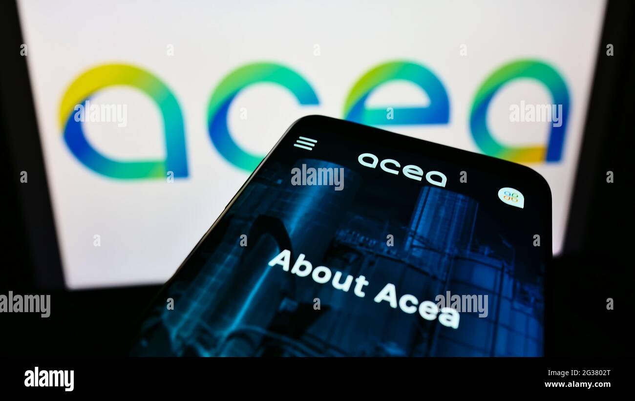 Smartphone con sito web della società di servizi italiana ACEA Spa sullo schermo davanti al logo aziendale. Mettere a fuoco in alto a sinistra del display del telefono. Foto Stock