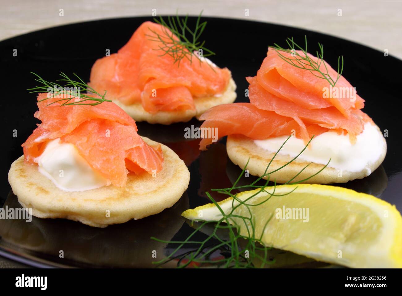 Frittelle Blinis servite con Crème Fraiche, salmone affumicato e guarnito con aneto. Foto Stock