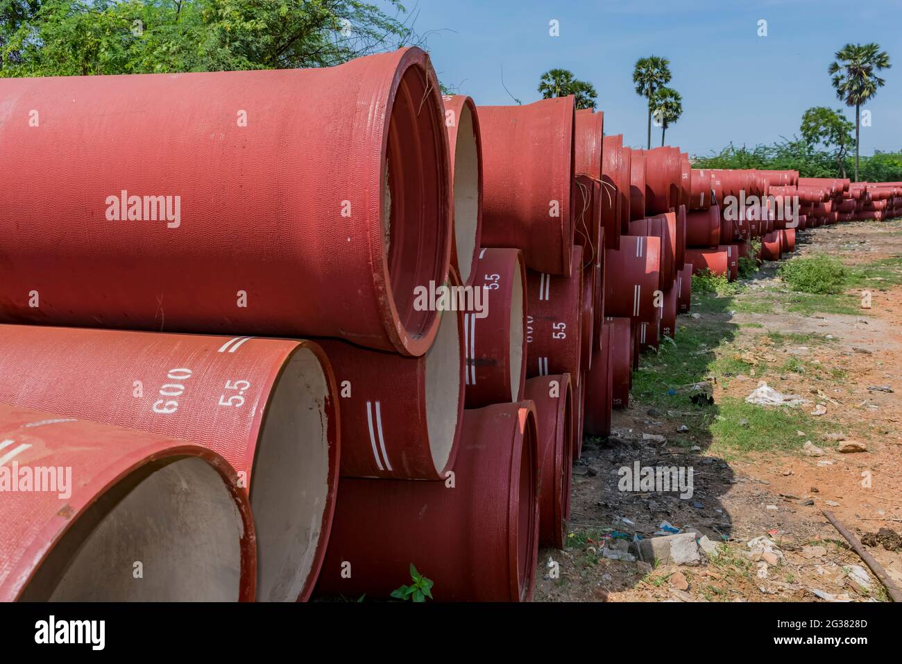 tubi di ferro duttile immagazzinato in spazio aperto di un cantiere rurale di deposito di villaggio. Foto Stock