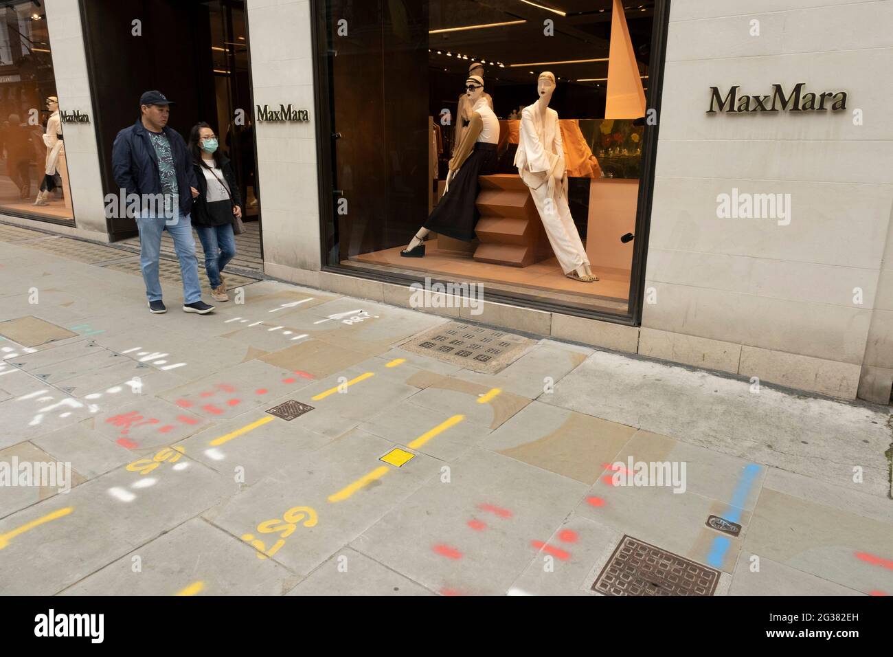 La gente passa il negozio Max Mara indossando maschere sulla Bond Street il  25 maggio 2021 a Londra, Regno Unito. Questi marchi di fascia alta sono  visti l'uno accanto all'altro su un
