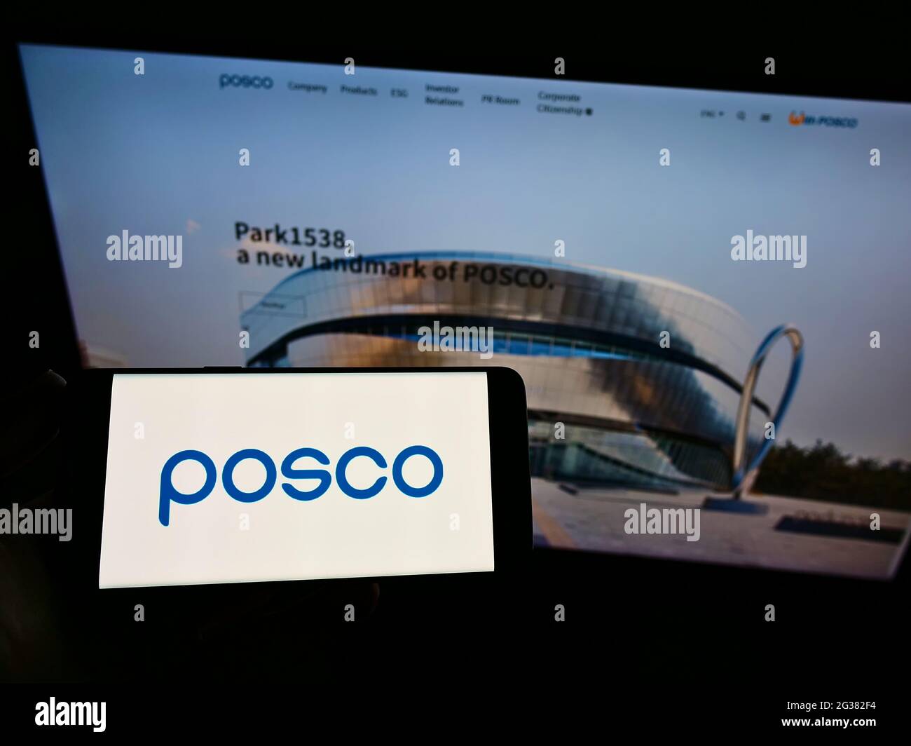 Persona che tiene il cellulare con il logo del produttore di acciaio sudcoreano POSCO sullo schermo di fronte alla pagina web aziendale. Mettere a fuoco il display del telefono. Foto Stock