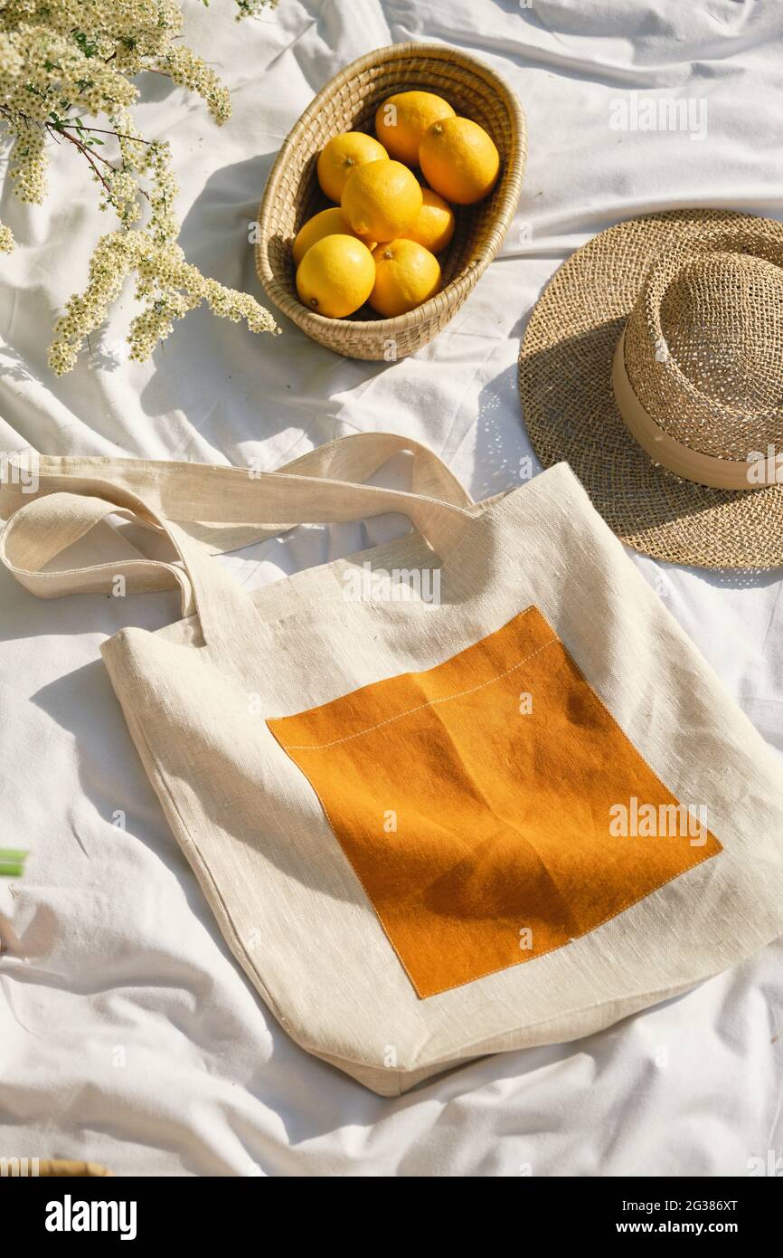 Piatto da borsa di tessuto shopping, cappello di paglia e cestino di limone. Stile di vita sostenibile senza plastica. Foto Stock