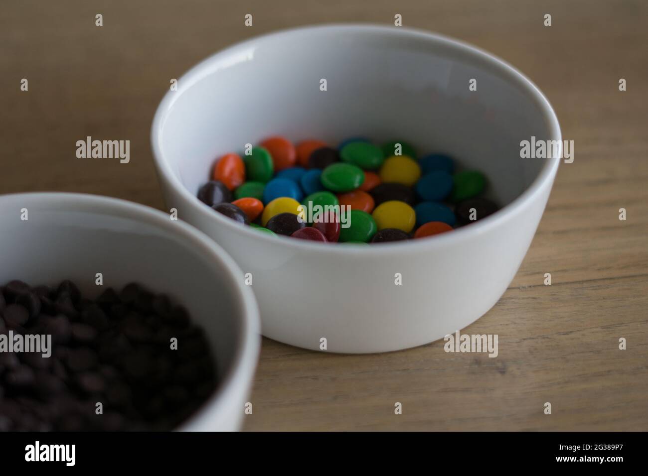 Ingredienti diversi di un biscotto in ciotole bianche messo su un tavolo da cucina in legno Foto Stock