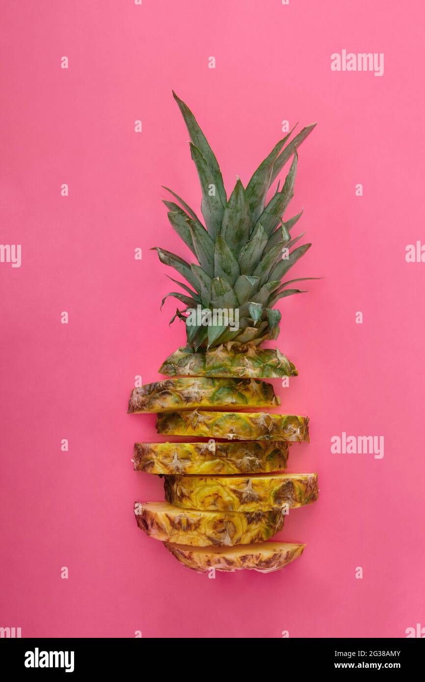 Ananas a fette su sfondo estivo di colore rosa. Anelli di ananas a fette di frutta tropicale. Composizione creativa piatta Foto Stock