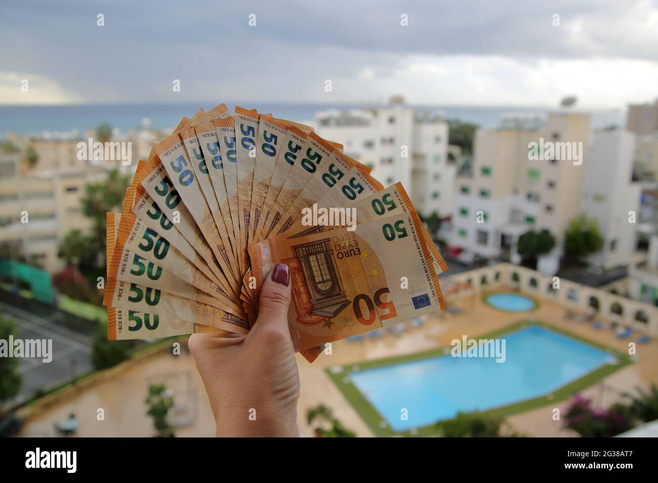 Gamma di banconote da 50 euro in clsoe up femminile a mano, in edifici di background, immobili, piscina, vacanze, economia, finanze, investire, prezzo. Foto Stock