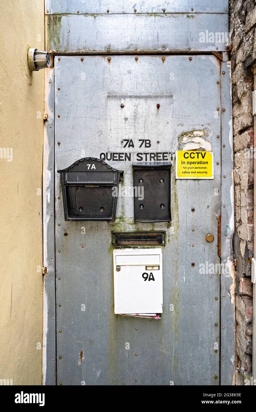 Porta in metallo alla fine del vicolo con scatole di posta danneggiate Foto Stock
