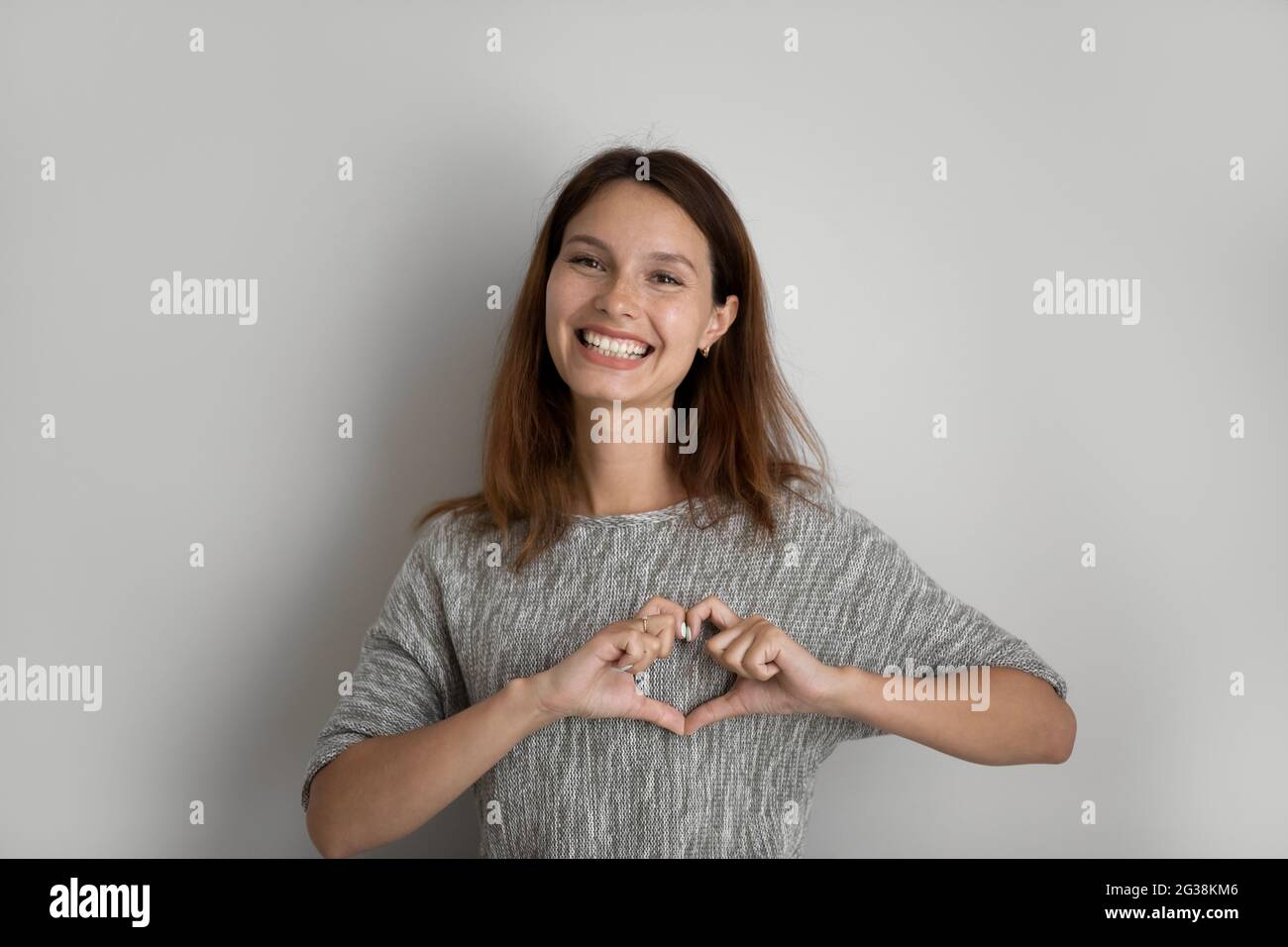 Ritratto della testa di una donna sorridente e attraente che mostra un gesto del cuore Foto Stock