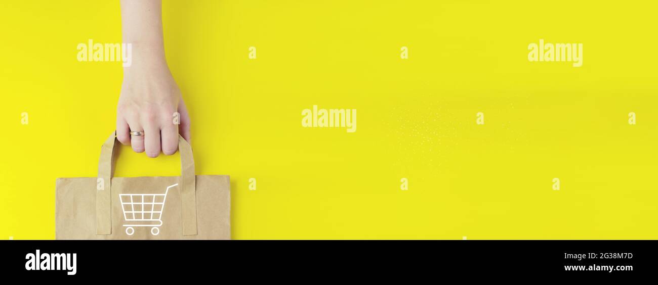 Offerta estiva. E-commerce Aggiungi al carrello online shopping concetto di Internet. Borsa della spesa in carta marrone riciclata in mano con ologramma icona del carrello della spesa su YE Foto Stock