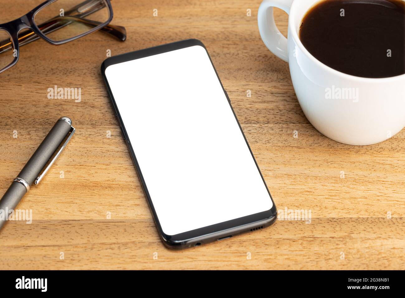 Modello mockup smartphone con tazza da caffè e occhiali su tavolo in legno. Schermo bianco Foto Stock