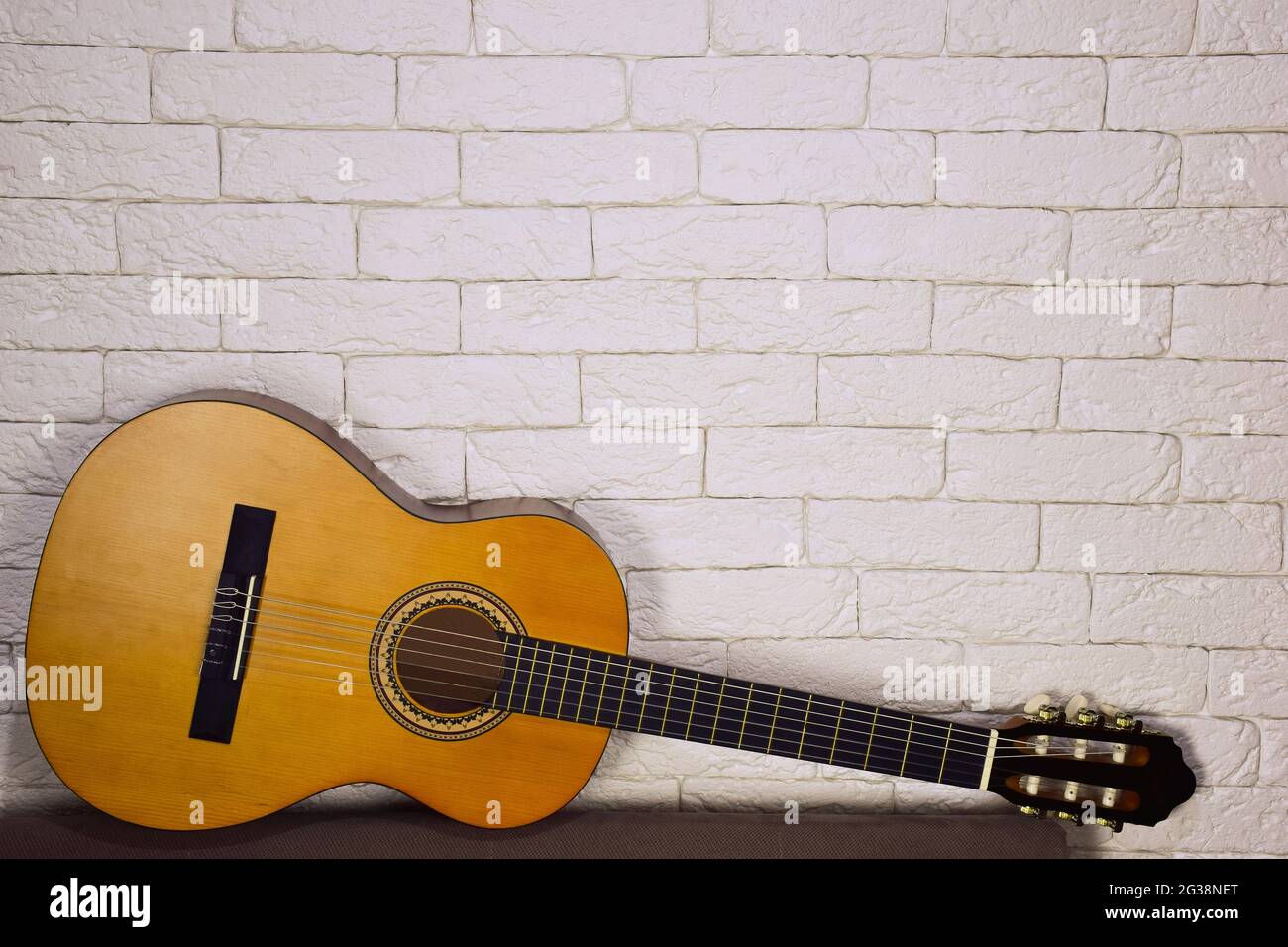 Sotto, contro una parete decorativa fatta di mattoni leggeri, si trova una chitarra acustica in legno. Ci è un posto per la pubblicità sopra esso. Foto Stock