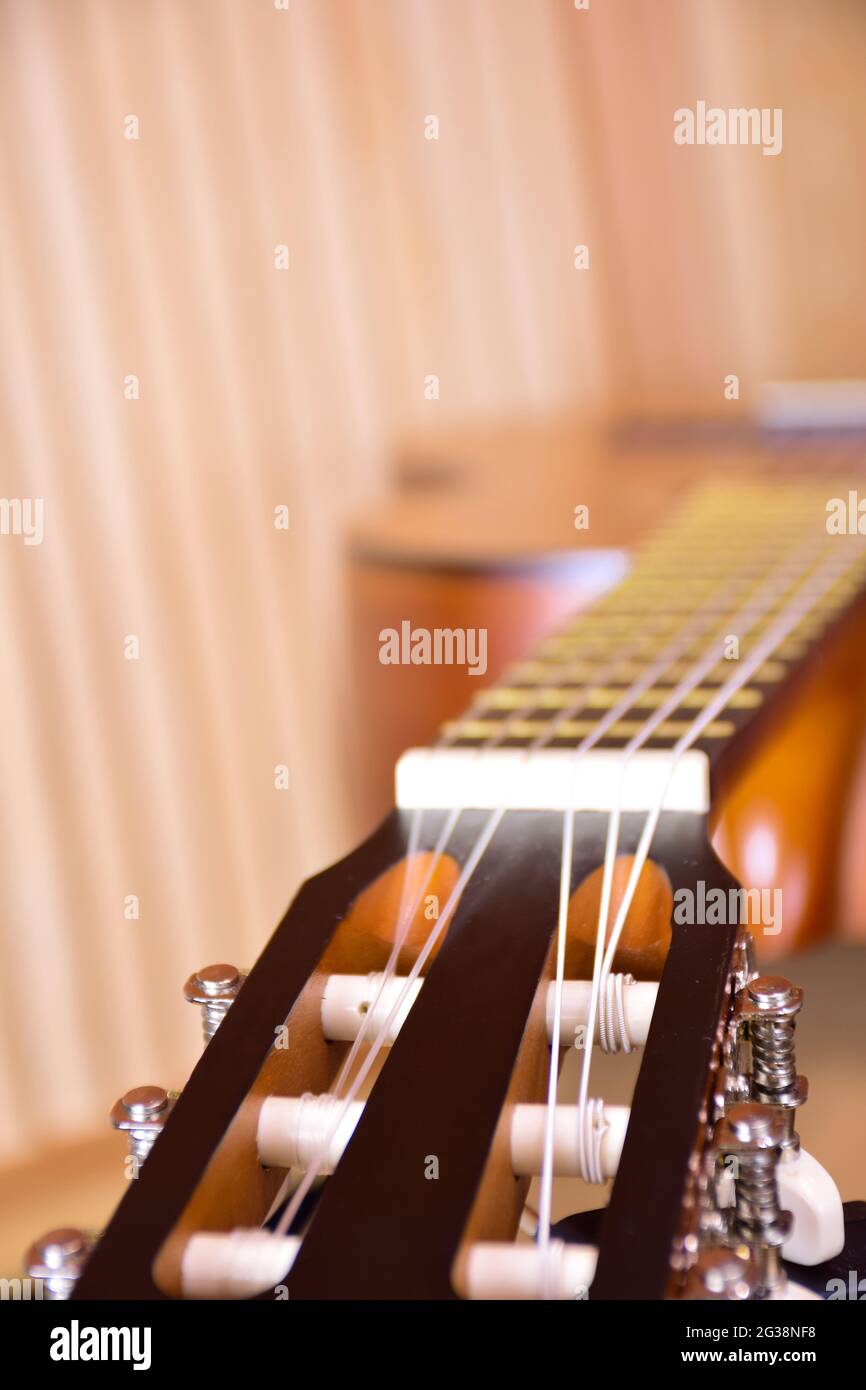 Sul lato si trova una chitarra acustica in legno da vicino. Cornice prospettica con sfondo molto sfocato Foto Stock