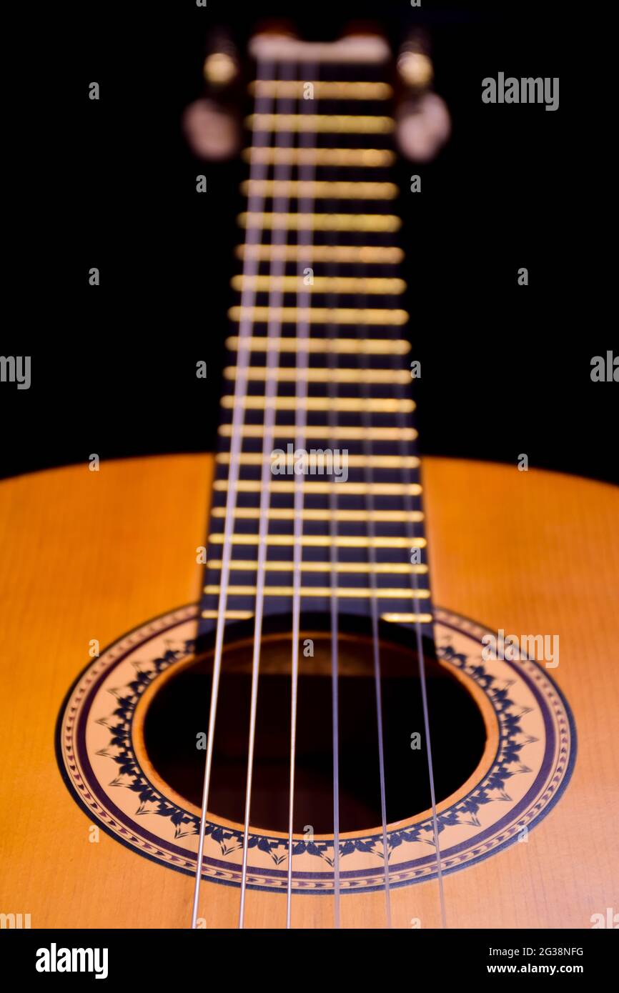 Sul lato si trova una chitarra acustica in legno da vicino. Cornice prospettica con sfondo molto sfocato Foto Stock