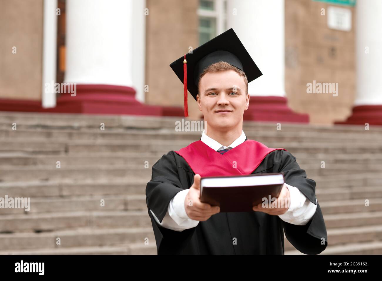 Ritratto di studente di laurea maschile con libro all'aperto Foto Stock