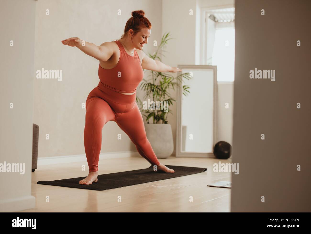 Donna in forma che si esercita a casa su tappetino fitness. Donna in abbigliamento sportivo che fa allenamento yoga in palestra. Foto Stock