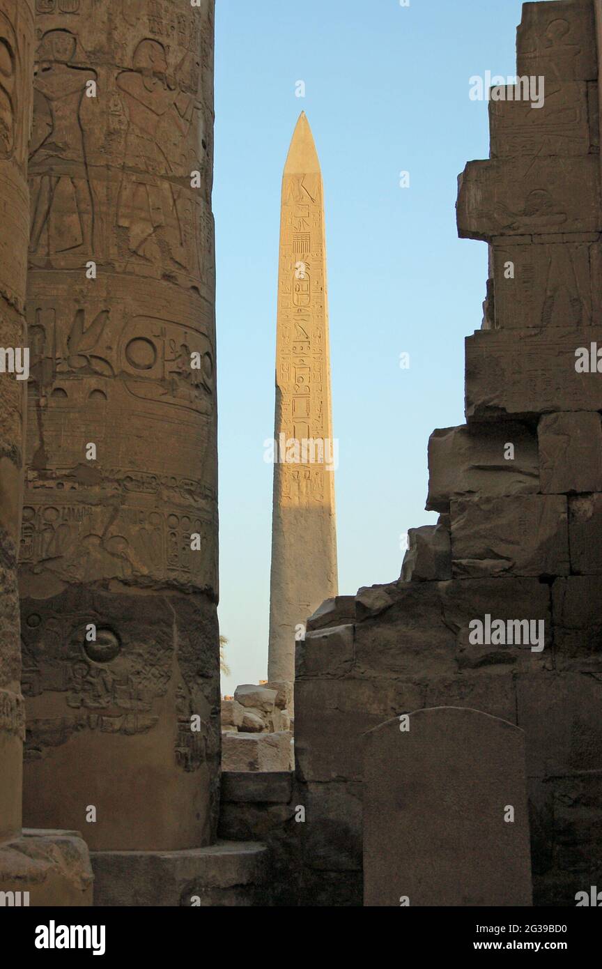 Un antico obelisco di pietra egiziano che cattura il sole dorato alle rovine del Tempio di Karnak a Luxor, Egitto. Foto Stock