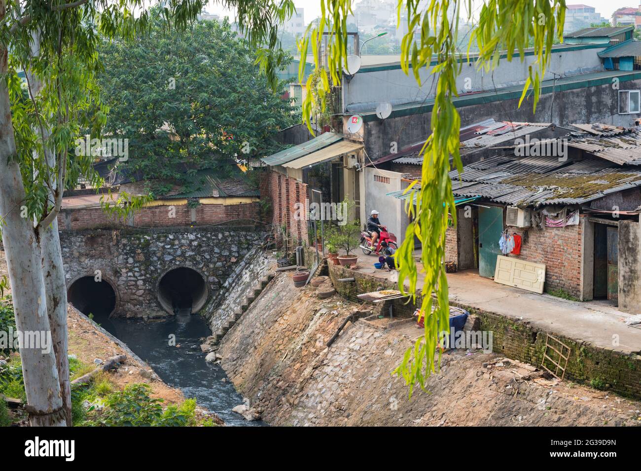 Un motociclista che entra in un'allyway accanto ad un fiume in una residenza si trova ad Hanoi, in Vietnam Foto Stock
