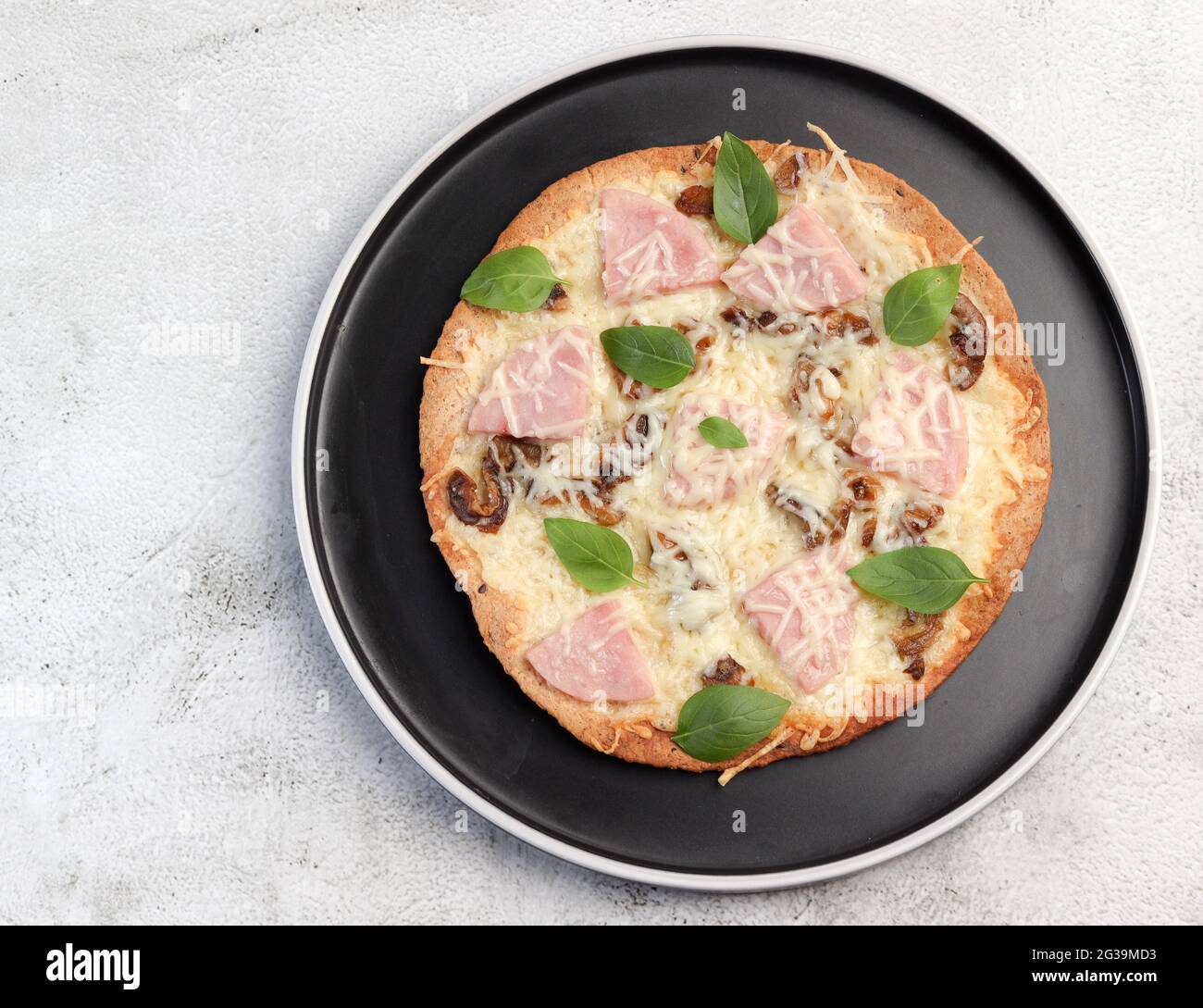 Tortilla con formaggio, funghi e prosciutto su un piatto rotondo su fondo grigio chiaro. Vista dall'alto, disposizione piatta Foto Stock