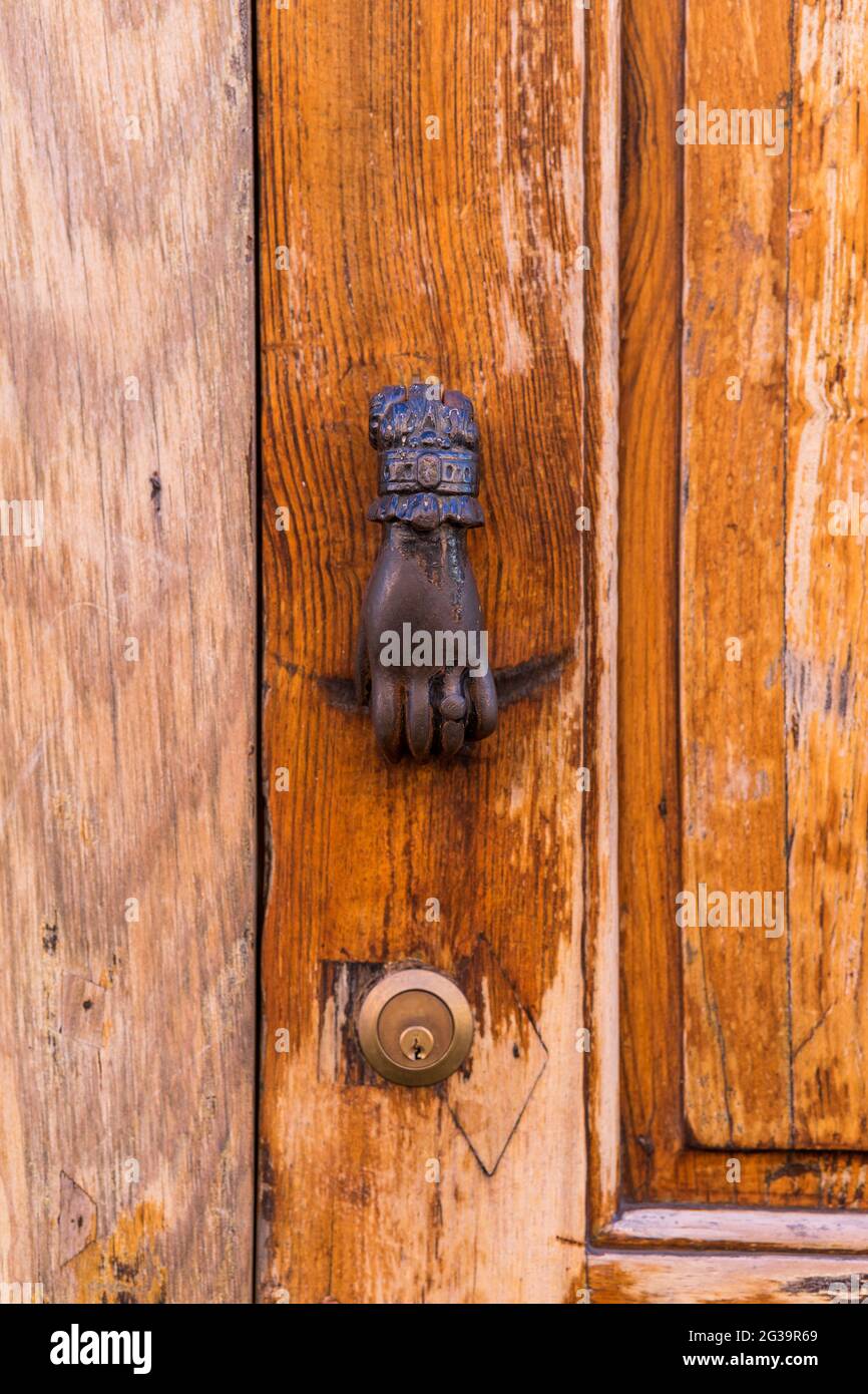 Colpo verticale di una vecchia porta in legno di noce con un batticalcagno vintage a forma di mano Foto Stock