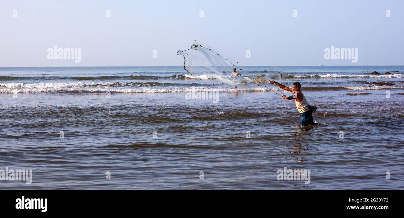 Vista panoramica del pescatore indiano getta enorme rete di pesca attraverso l'acqua, Agonda, Goa, India Foto Stock