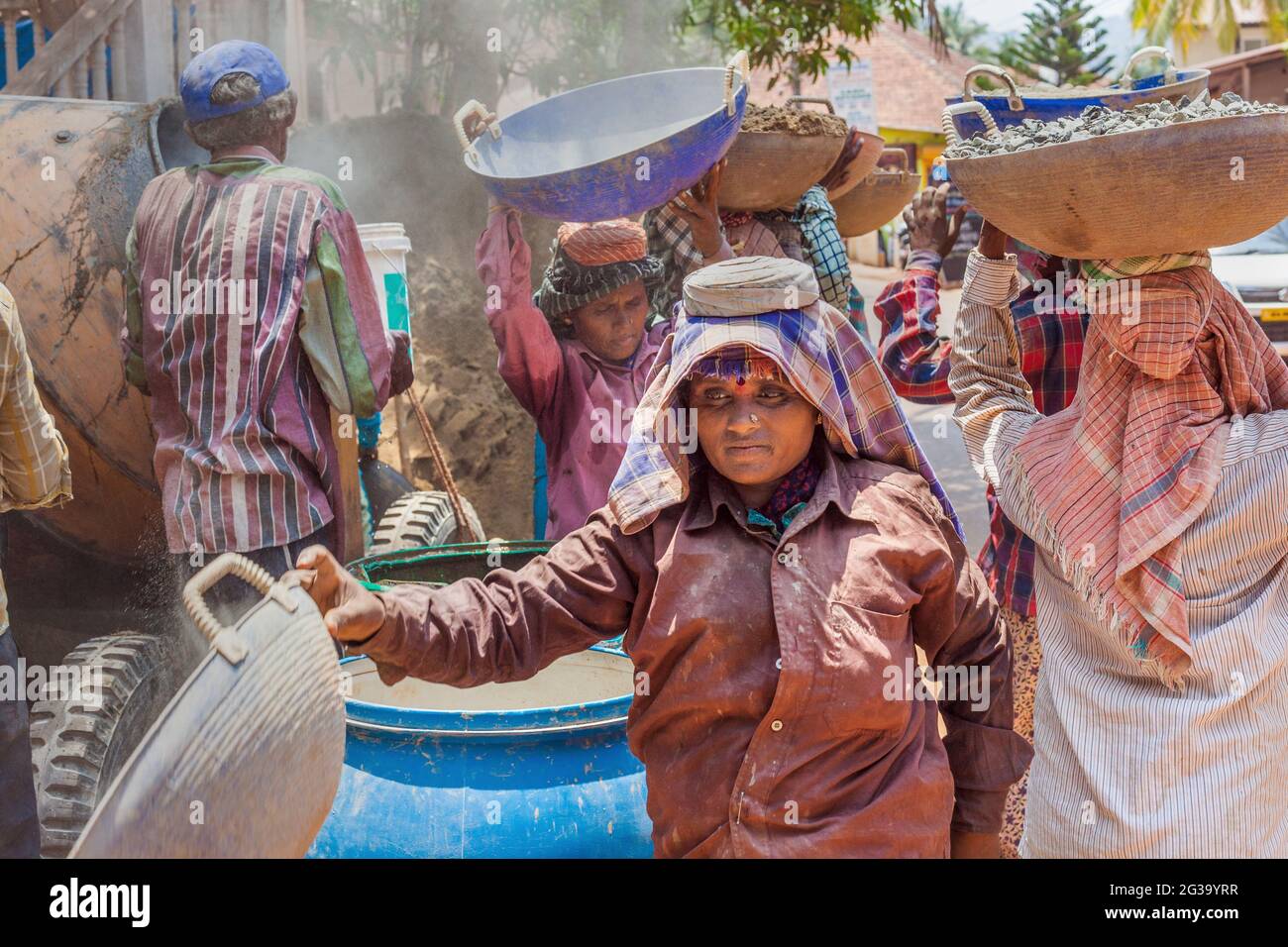 Lavoratrici indiane manuali che trasportano carichi pesanti sulle loro teste in cantiere, Agonda, Goa, India Foto Stock