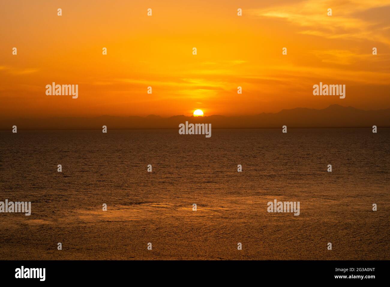 Tramonto arancione minimo sul Mar Rosso e sulle montagne sudanesi all'orizzonte, serata tranquilla, visto da una nave. Foto Stock