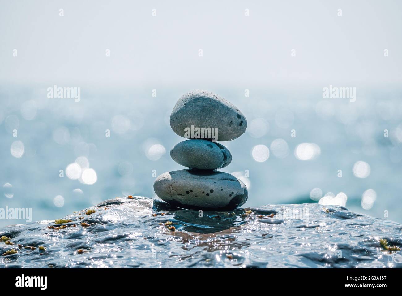Equilibrata piramide di ciottoli sulla spiaggia in una giornata di sole. Abstract Sea bokeh sullo sfondo. Messa a fuoco selettiva. Pietre Zen sulla spiaggia di mare, meditazione Foto Stock