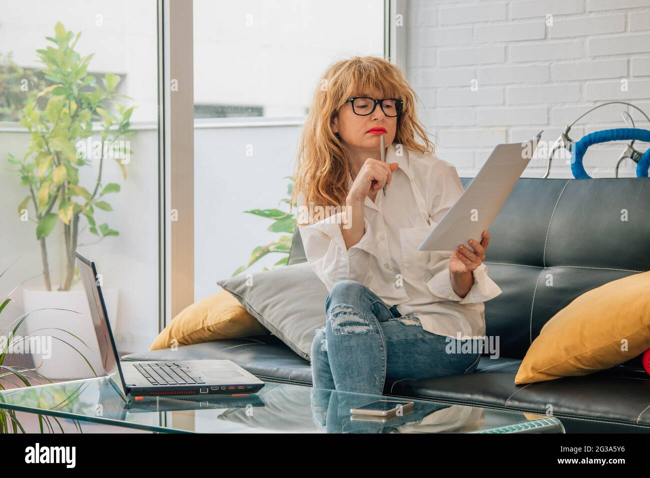 donna d'affari che lavora a casa con computer e documenti online Foto Stock