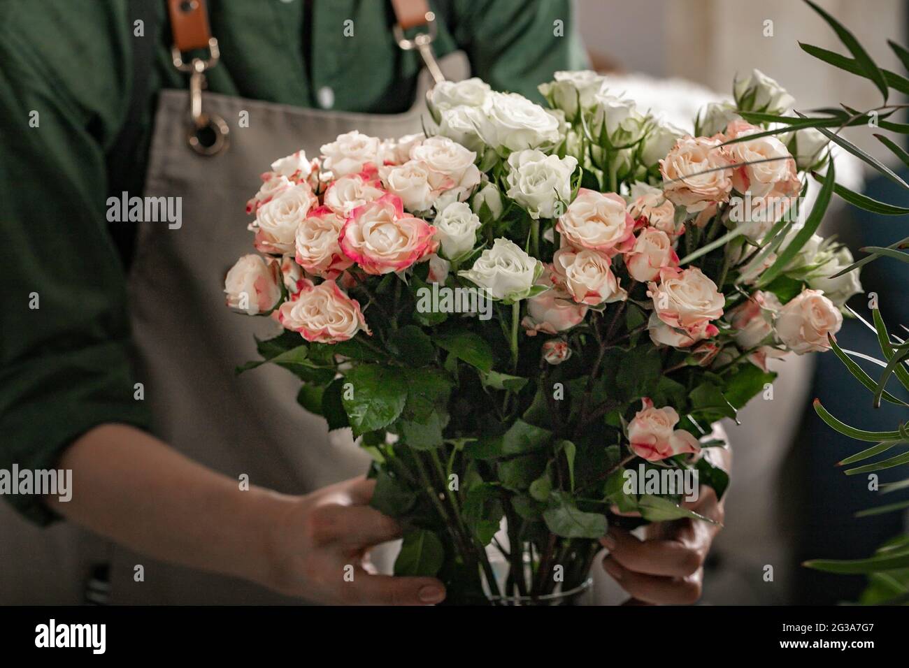 Fiorista sta tenendo un grande bouquet di rose. Ambiente di lavoro fiorista. Concetto di piccola impresa. Negozio di fiori e accessori. Primo piano Foto Stock
