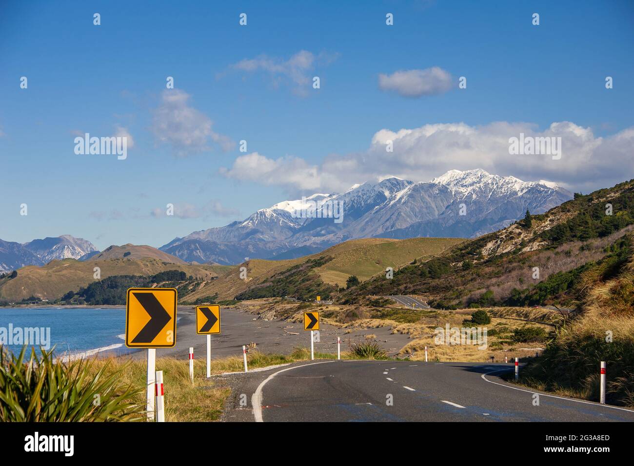 State Highway 1, iconica rotta costiera vicino a Kaikoura, Nuova Zelanda, una delle migliori strade costiere del mondo. Montagne innevate, mare, cielo e strada Foto Stock