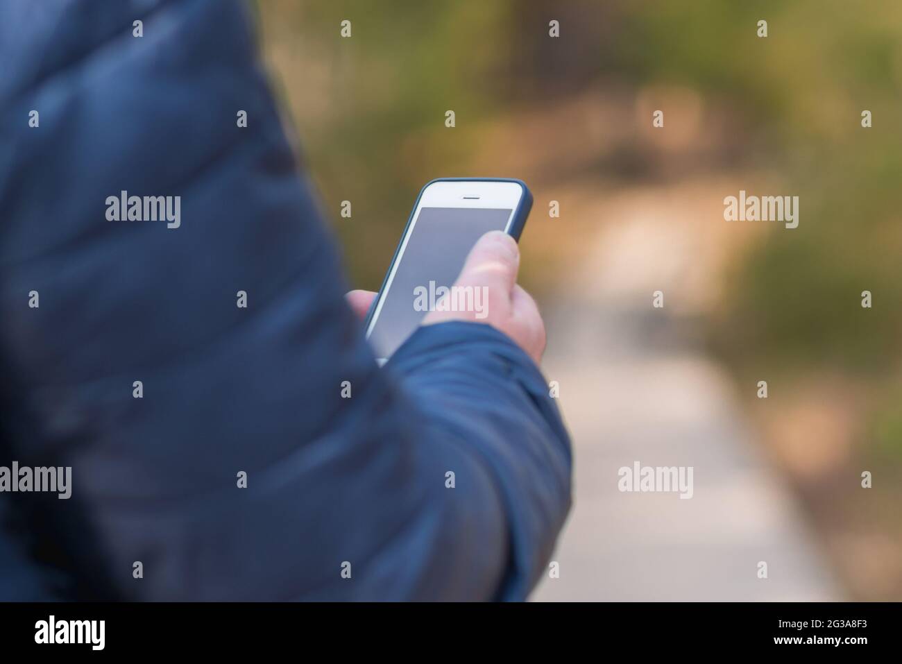 Un uomo di 40 anni con il suo smartphone cellulare alla ricerca del segnale di ricezione nella foresta primaverile. Foto Stock