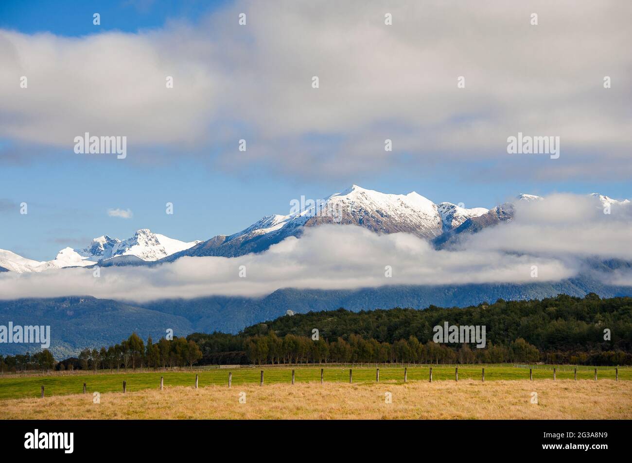 Paesaggio rurale, te Anau, Isola del Sud, Nuova Zelanda. Vista panoramica, catena montuosa innevata con nuvole di basso livello e terreni agricoli Foto Stock