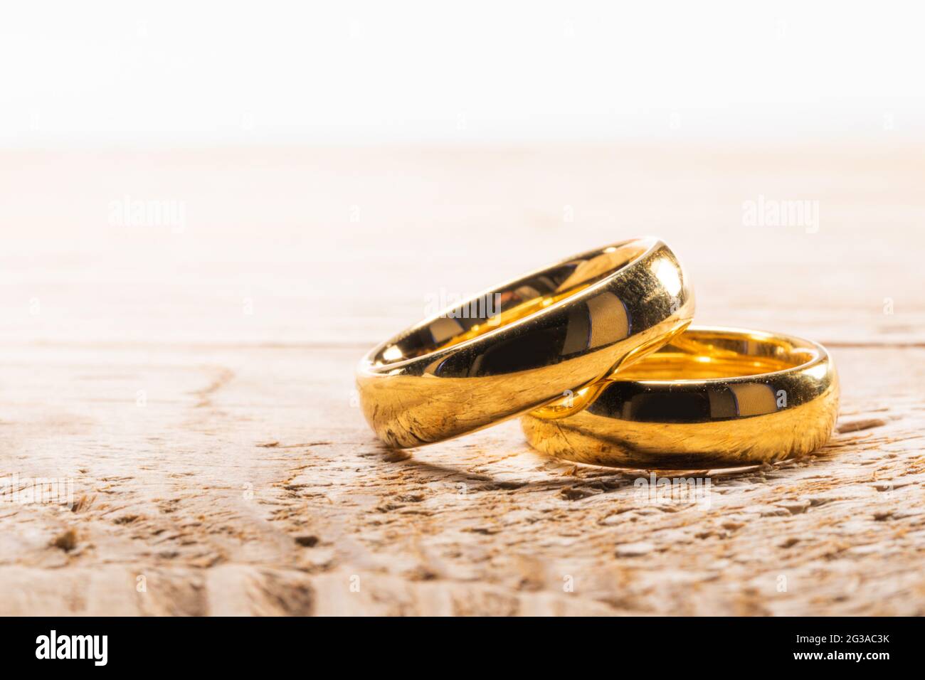 Due golden gli anelli di nozze su sfondo di legno con copia spazio per il testo Foto Stock