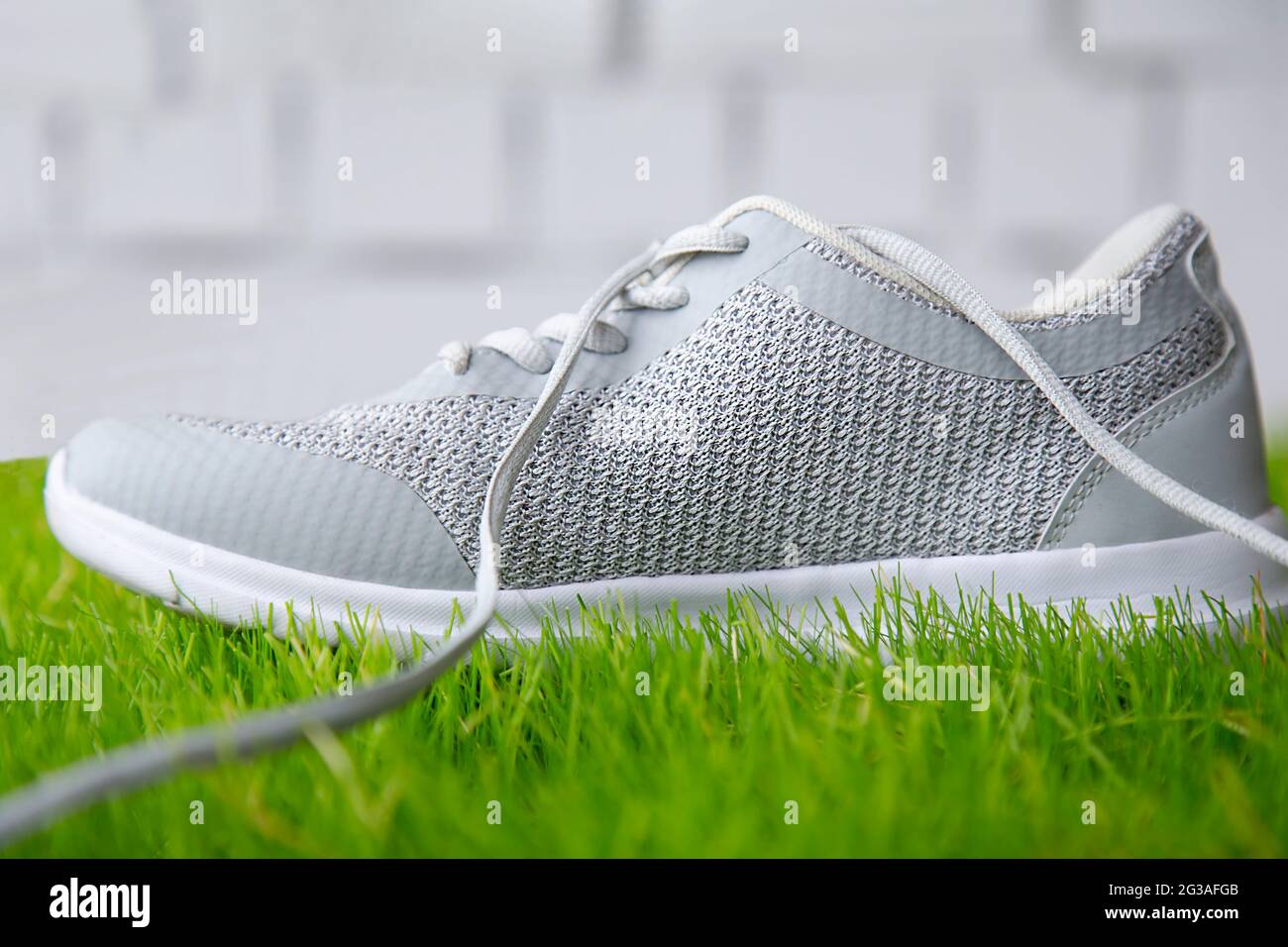 Scarpe sportive sull'erba contro un muro di mattoni. Scarpe per lo sport sul campo sportivo in erba prato. Foto Stock