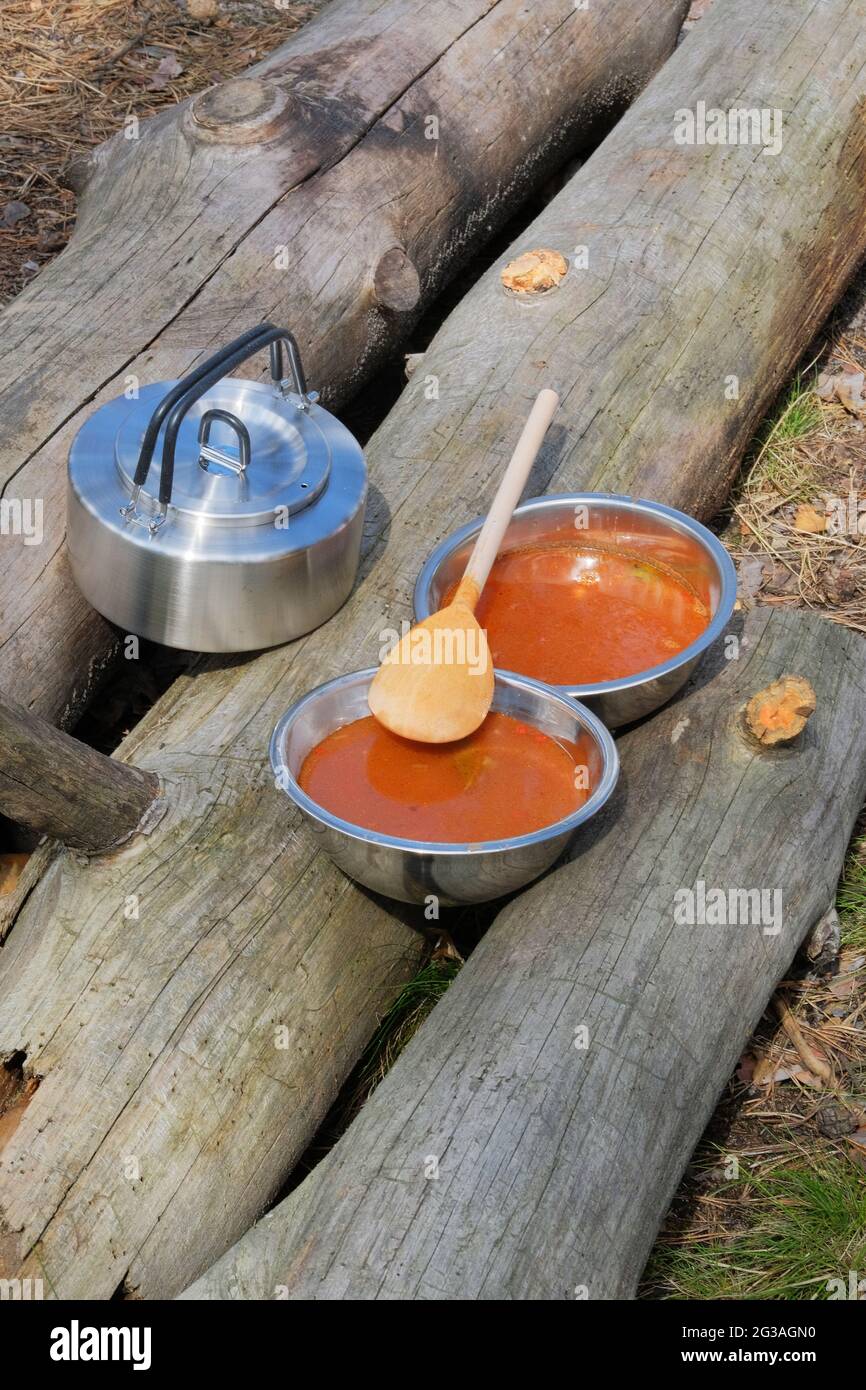 Il viaggiatore sta mangiando la zuppa durante il campeggio. Gustatevi un cibo gustoso durante le escursioni. Cibo turistico per attività all'aperto. Foto Stock