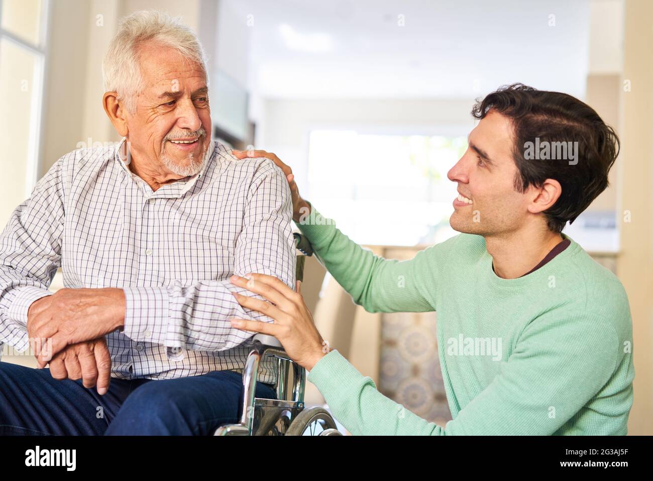 Uomo che si prende cura di padre anziano in sedia a rotelle in casa di riposo o a casa Foto Stock