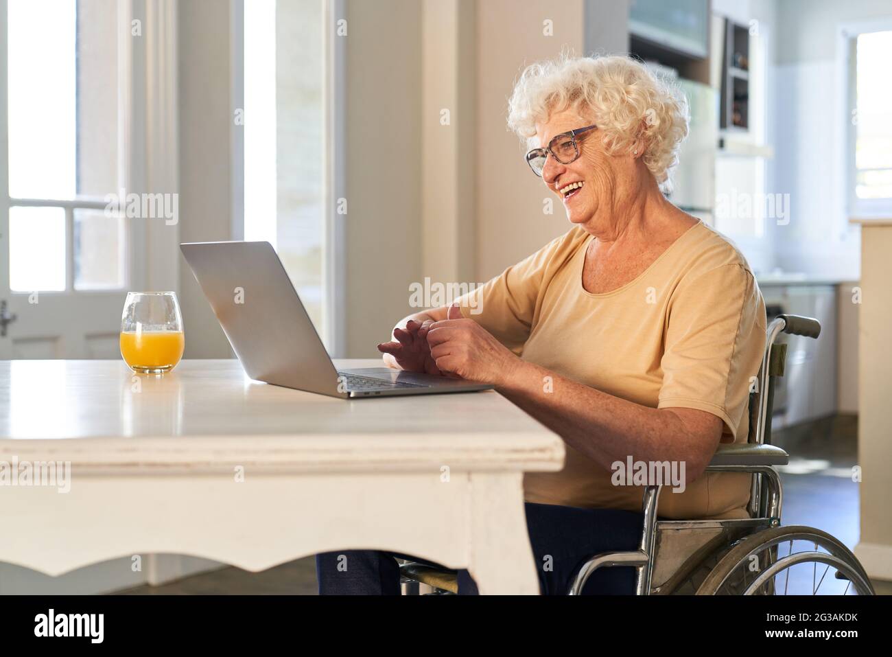 Buon anziano in sedia a rotelle che effettua una videochiamata con un PC portatile per il compleanno a casa Foto Stock