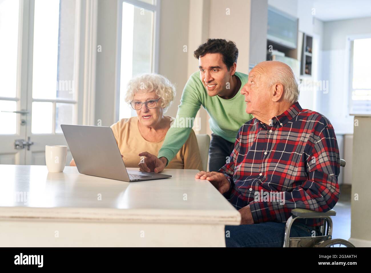 Son aiuta i genitori anziani con Internet e videochiamata su computer portatile a casa Foto Stock