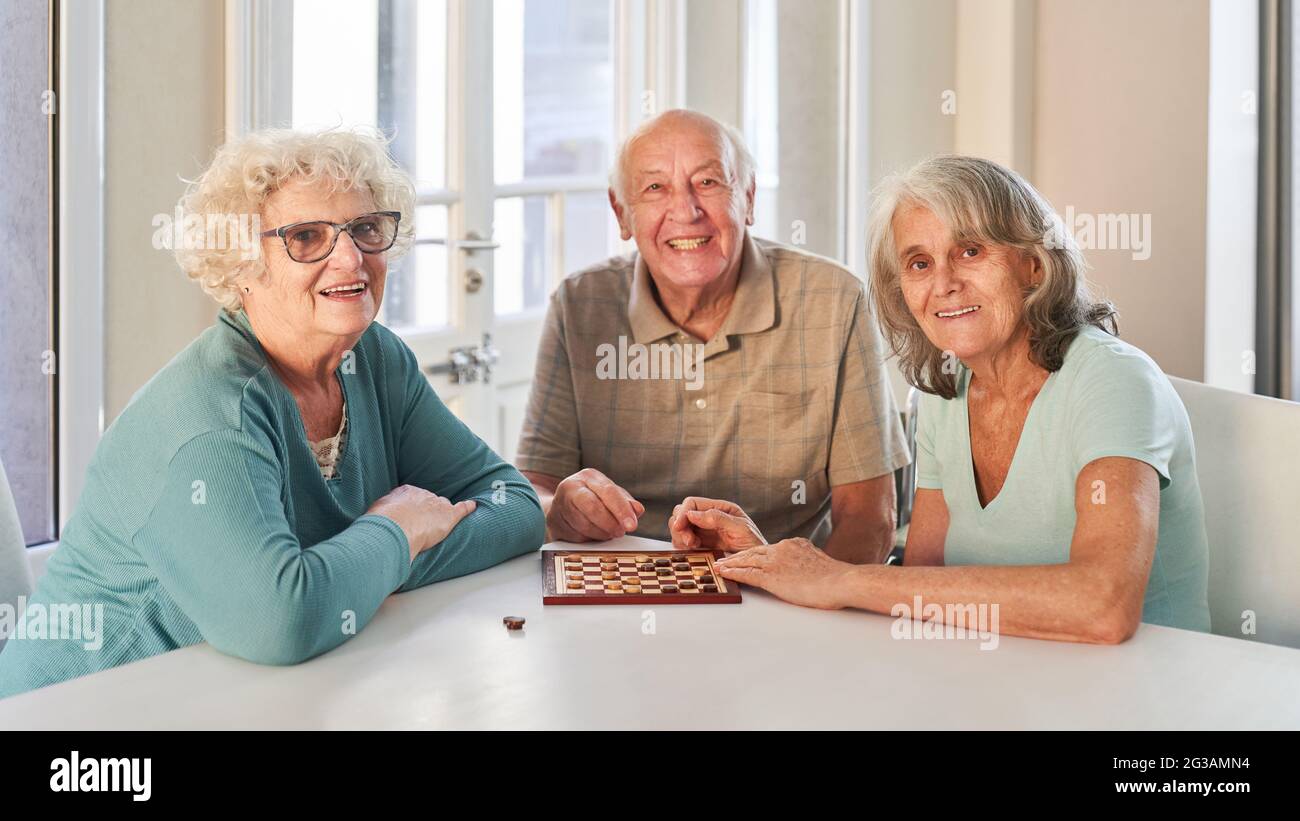 Gruppo di anziani come pensionati che giocano a scacchi insieme in casa di riposo o a casa Foto Stock