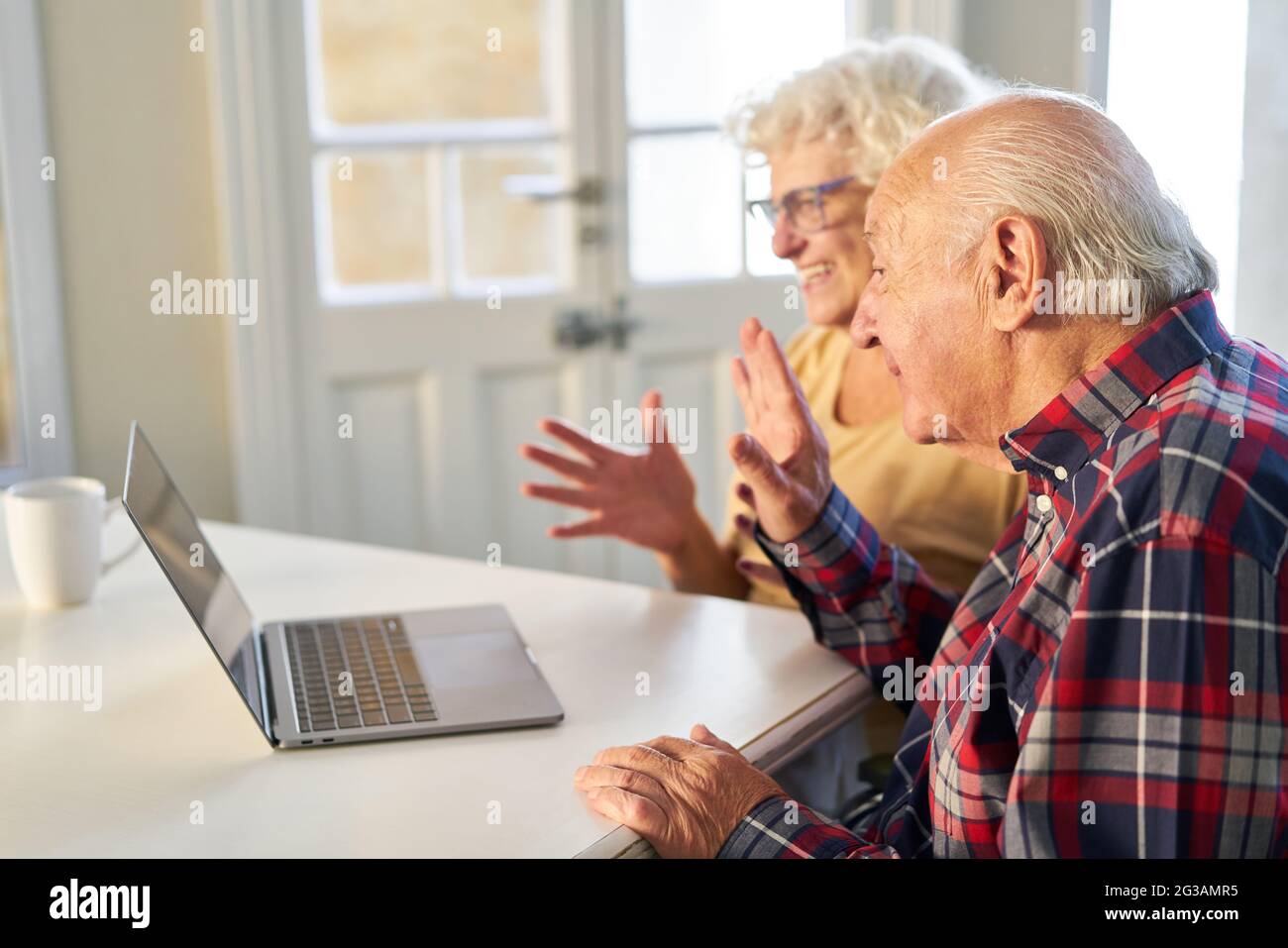 Coppia senior che si gode di una chat video con la famiglia su un computer portatile a casa Foto Stock