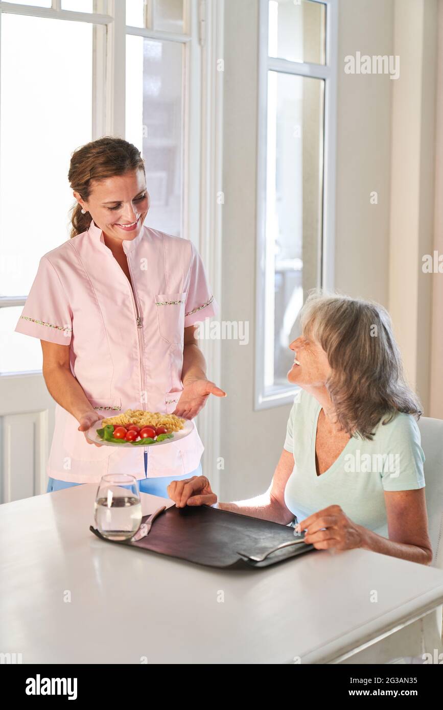 La donna anziana ottiene il cibo su ruote consegnato dal servizio di consegna o servito dal personale infermieristico Foto Stock