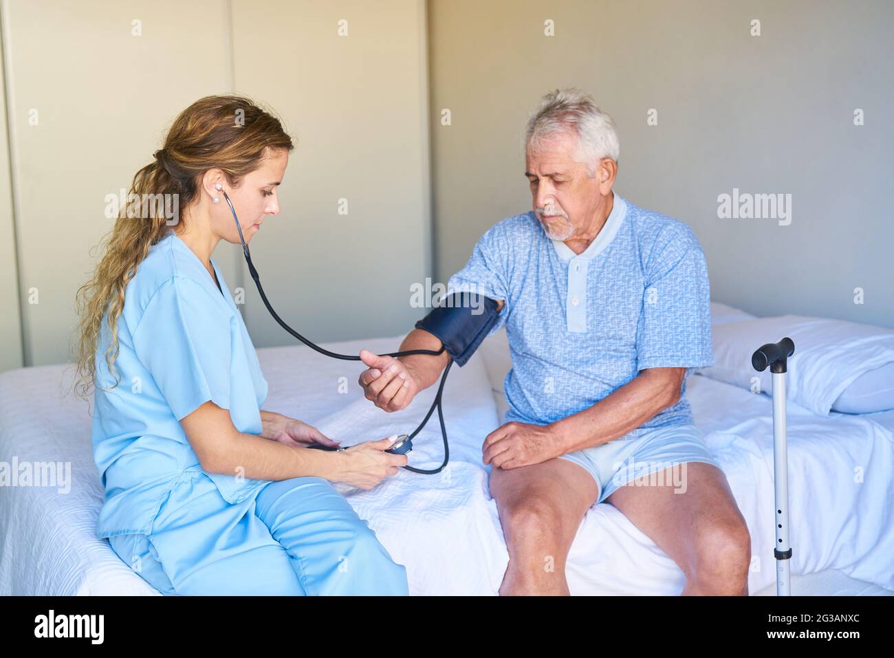 Infermiere che misura la pressione sanguigna di un anziano in ospedale o in casa di riposo Foto Stock