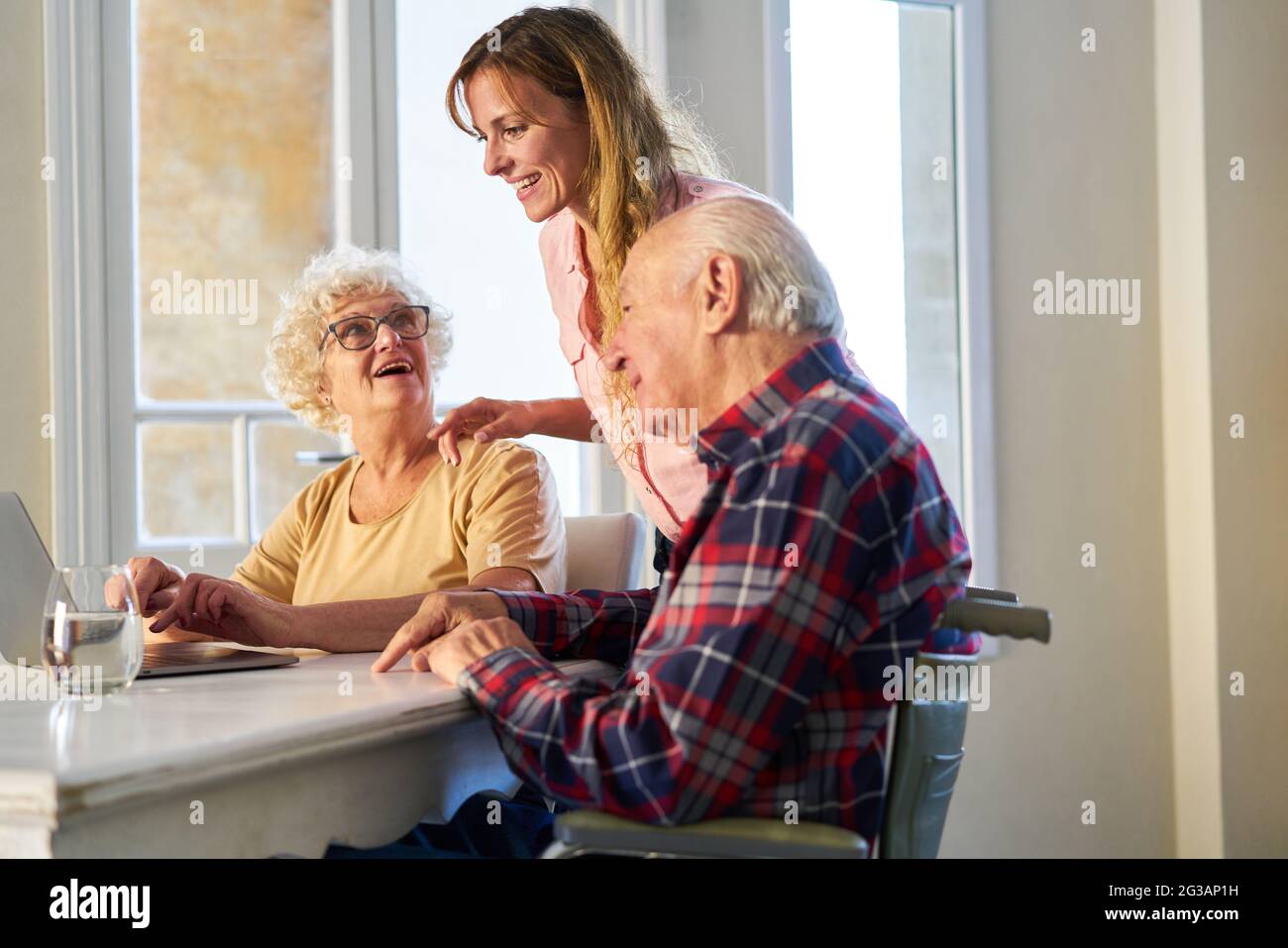 La giovane donna supporta i genitori anziani con la comunicazione dei social media su un computer portatile Foto Stock