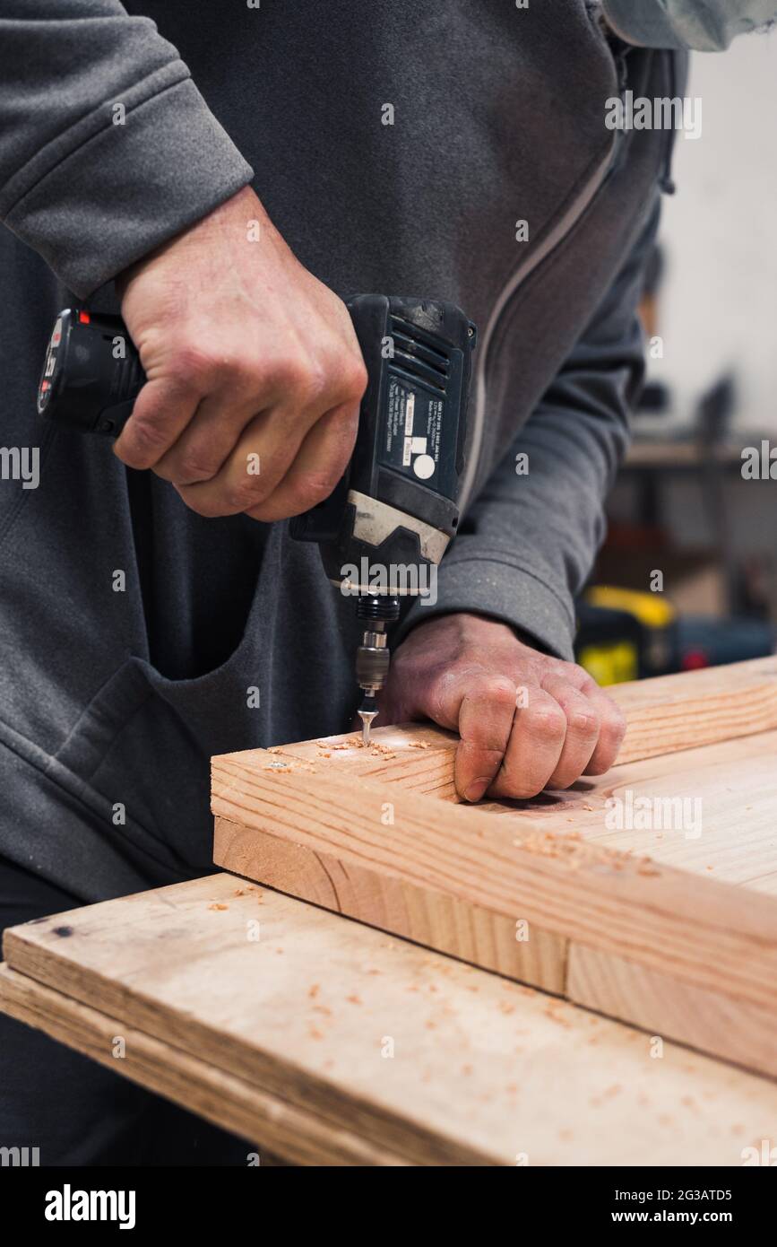 primo piano con il carpentiere avvitando una vite con un cacciavite elettrico Foto Stock