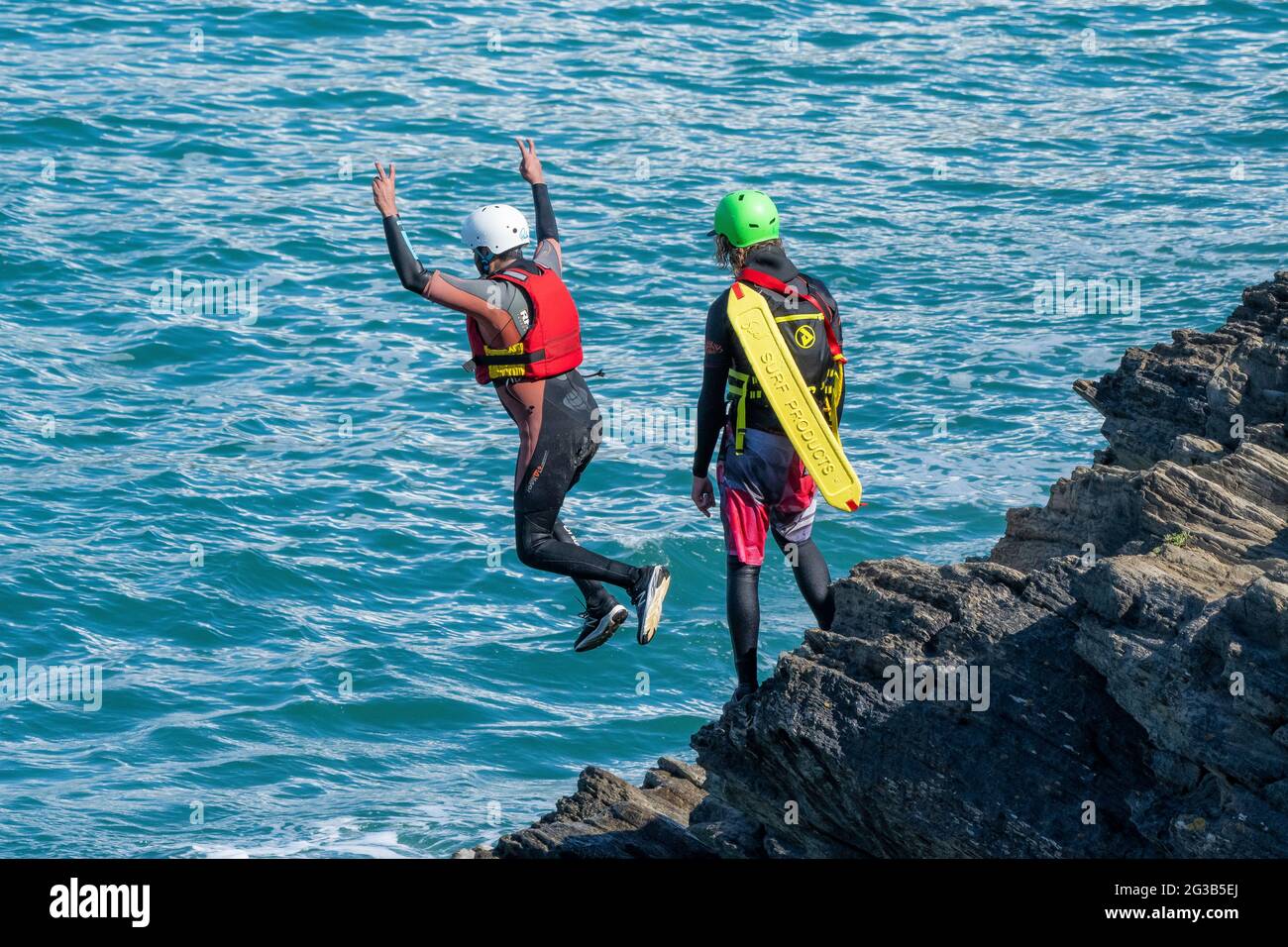 I vacanzieri saltano dalle rocce costellando con una guida su Towan Head a Newquay in Cornovaglia. Foto Stock