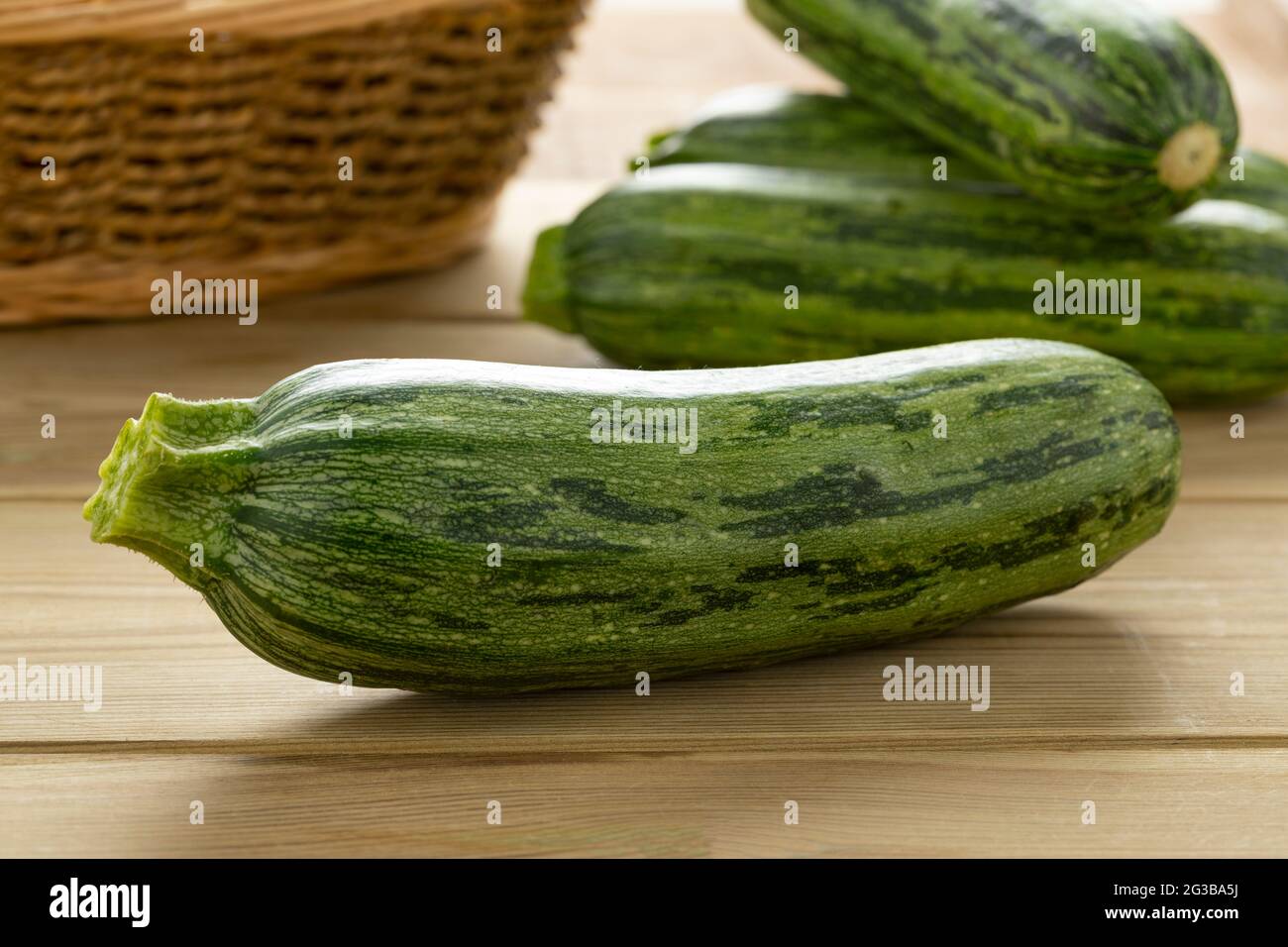 Una singola zucchina fresca macchiata di verde crudo su una cuttingboard primo piano Foto Stock