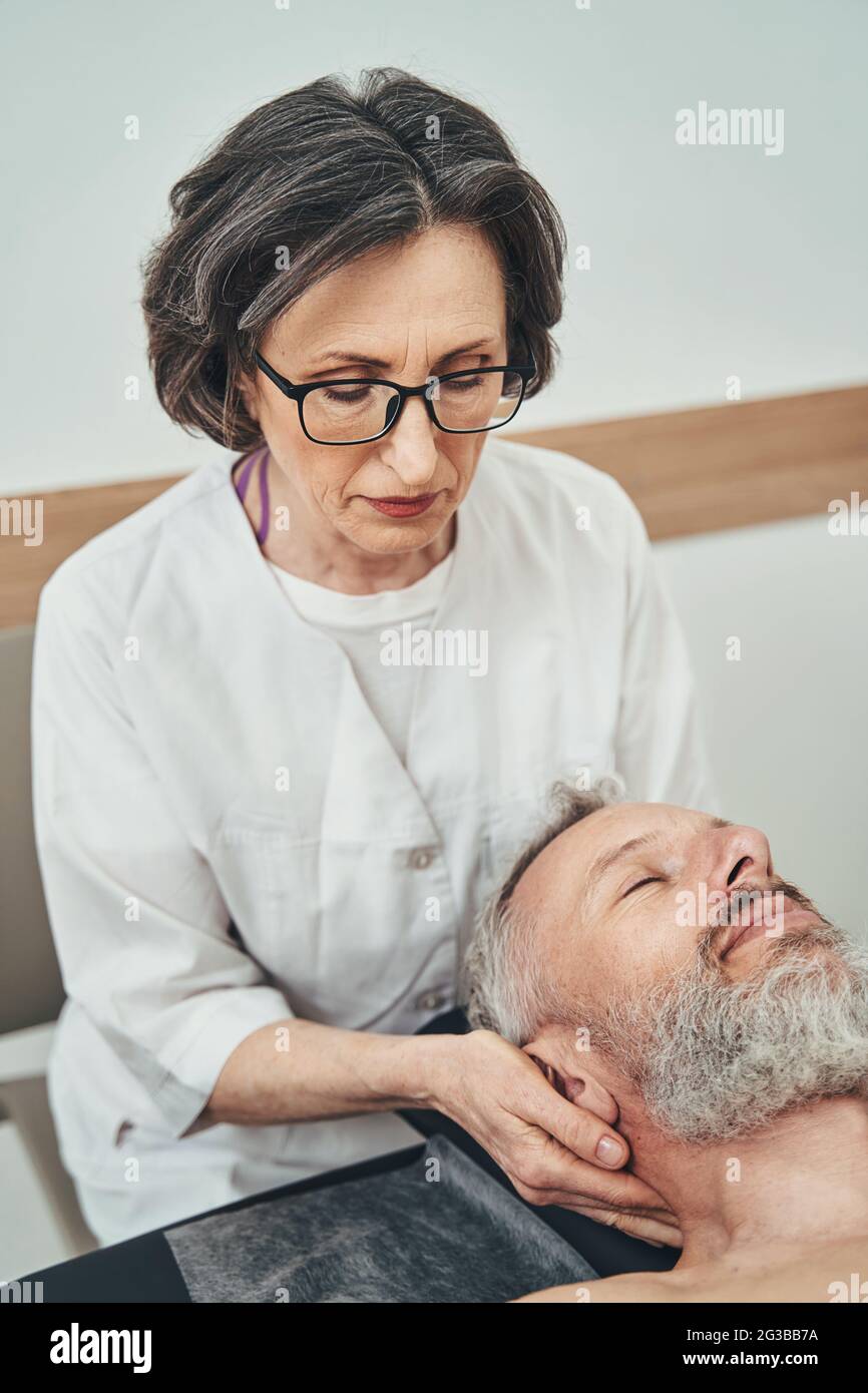 Chiropratico qualificato che utilizza una tecnica di rilascio di tessuto molle suboccipitale Foto Stock