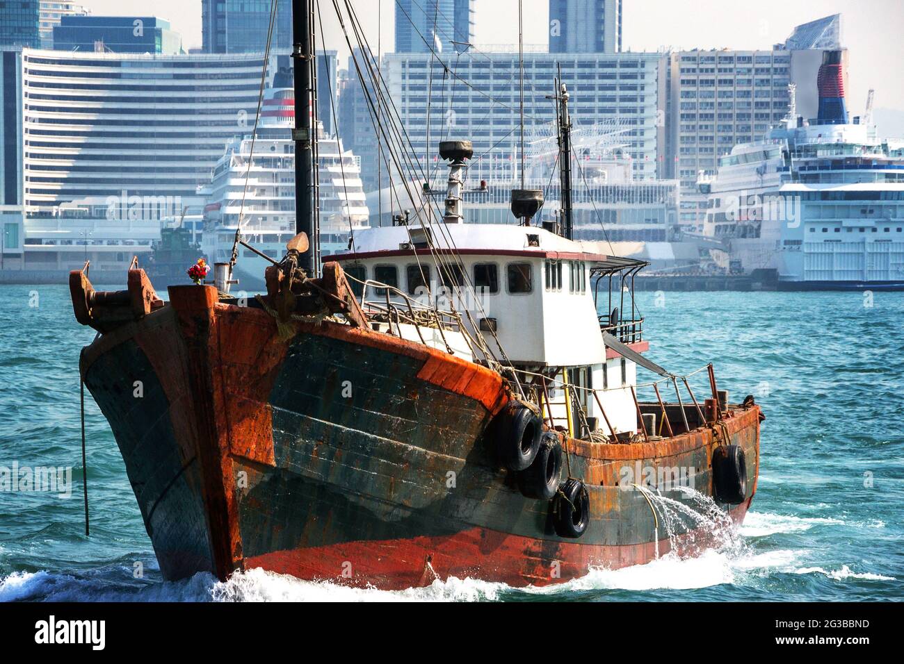 Vecchia nave da pesca con grattacieli di Hong Kong in background. Paesaggio di Hong Kong Foto Stock